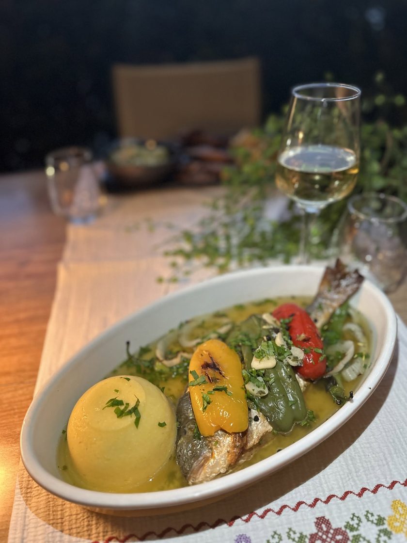 Sea bream in a herb brine with peppers and a dome of polenta, white wine behind